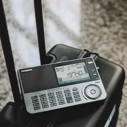 An ATS-909X2 shortwave radio sitting on top of luggage